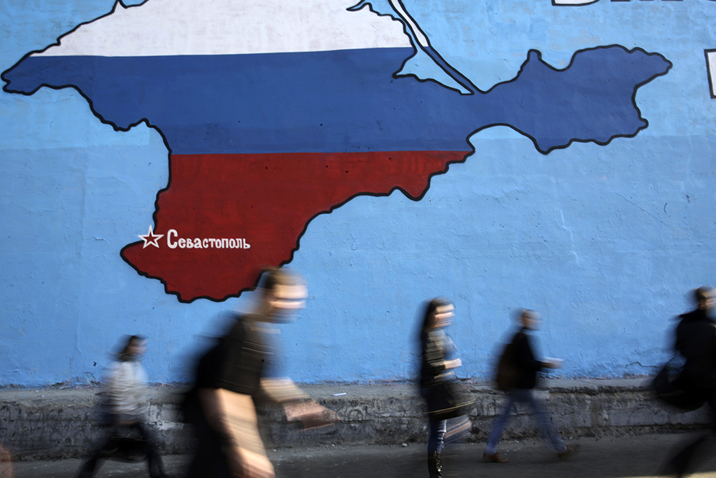 People pass a mural showing a map of Crimea in the Russian national colours on a street in Moscow March 25, 2014. NATO's top military commander said on Sunday Russia had built up a "very sizeable" force on its border with Ukraine and Moscow may have a region in another ex-Soviet republic, Moldova, in its sights after annexing Crimea. The map shows the location of the city Sevastopol. REUTERS/Artur Bainozarov (RUSSIA - Tags: POLITICS CIVIL UNREST TPX IMAGES OF THE DAY) - RTR3IH3Z